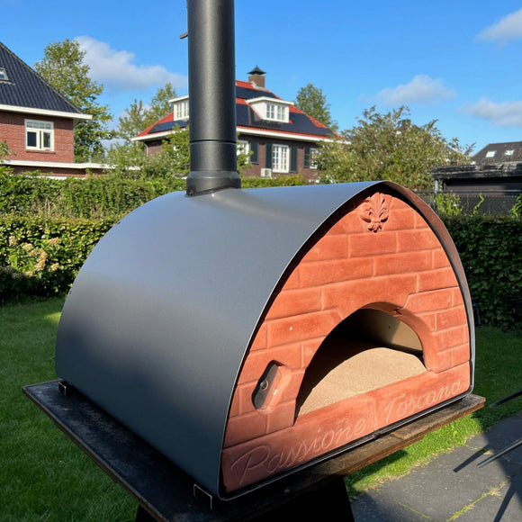 Outdoor pizza oven with brick design on a grassy area with houses in the background